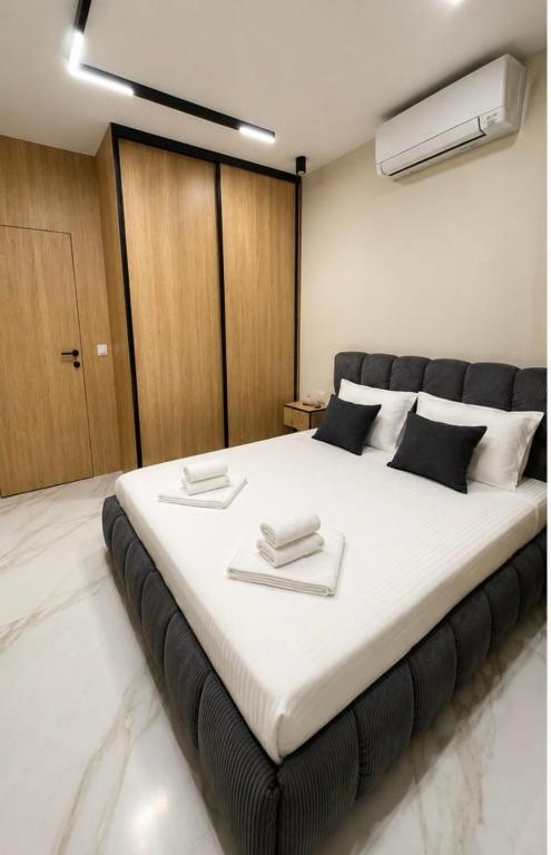 a bedroom with a large white bed with black accents at Nikol River Residence in Sandanski