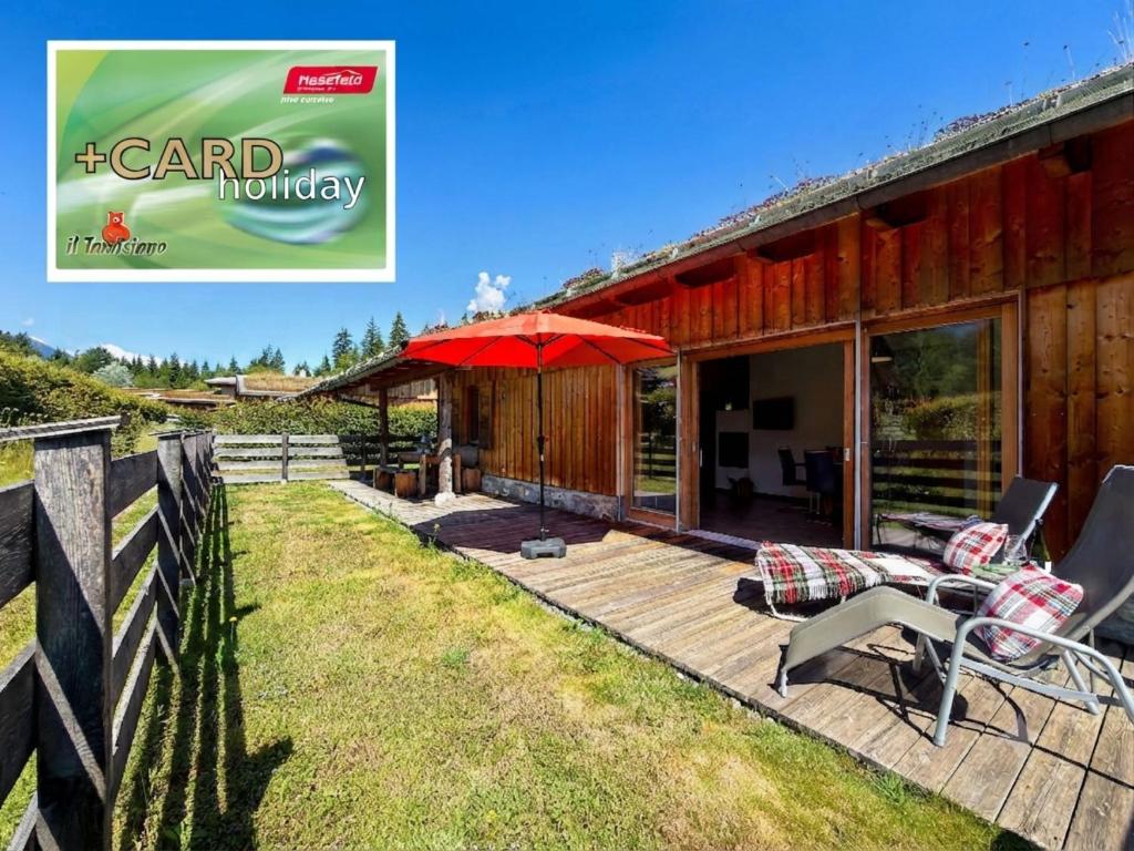 a house with a deck with a red umbrella at Trebas 51 in Lake Pressegg