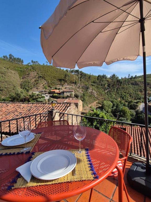 a red table with plates and an umbrella at Casa da Água Formosa in Vila de Rei