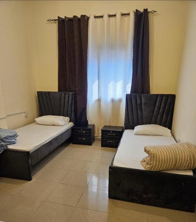 two beds sitting in a room with a window at Iman Guest House in Al Qurayyah