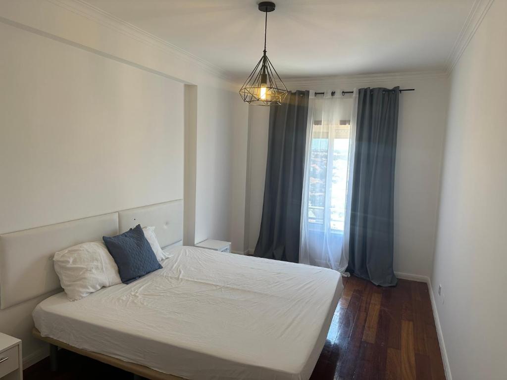 a bedroom with a white bed with a window at Renna in Corroios