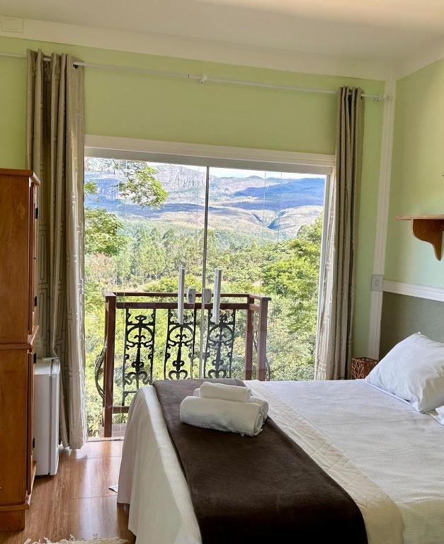 a bedroom with a bed and a large window at Pousada Canto do Luar in Conceição do Mato Dentro