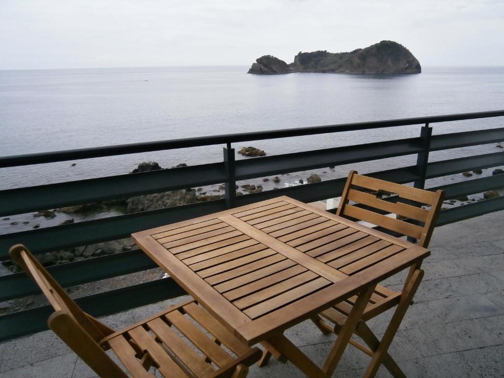 a wooden table and chair sitting next to the ocean at Casa Das Dias in Vila Franca do Campo