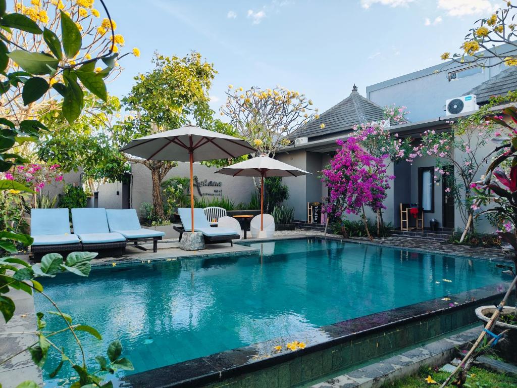 a pool with chairs and umbrellas next to a house at Ashana Hotel in Uluwatu