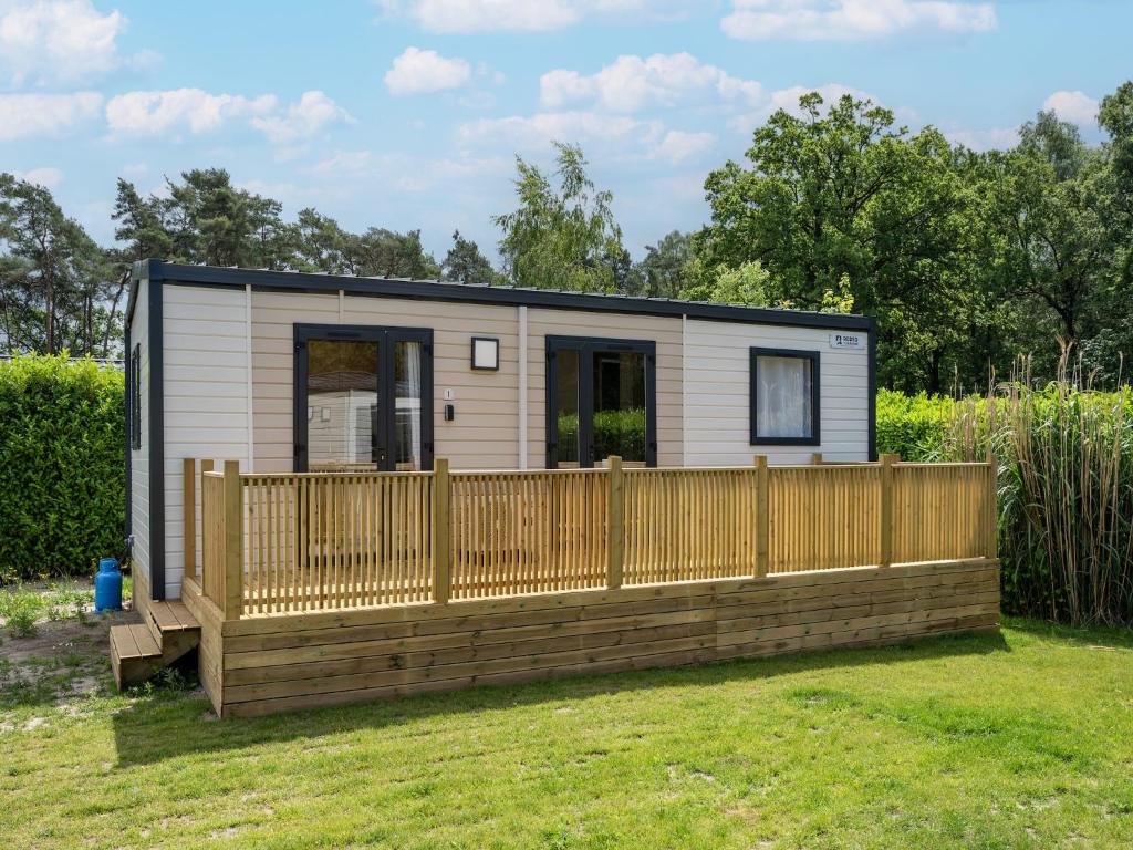 a tiny house with a wooden fence in a yard at Charming caravan with terrace for 6 in Vierhuizen