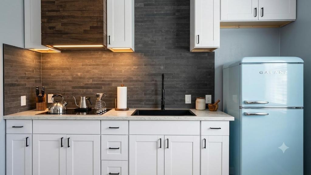 a kitchen with white cabinets and a blue refrigerator at Stylish Studio in Oleander Close to Downtown in Bakersfield