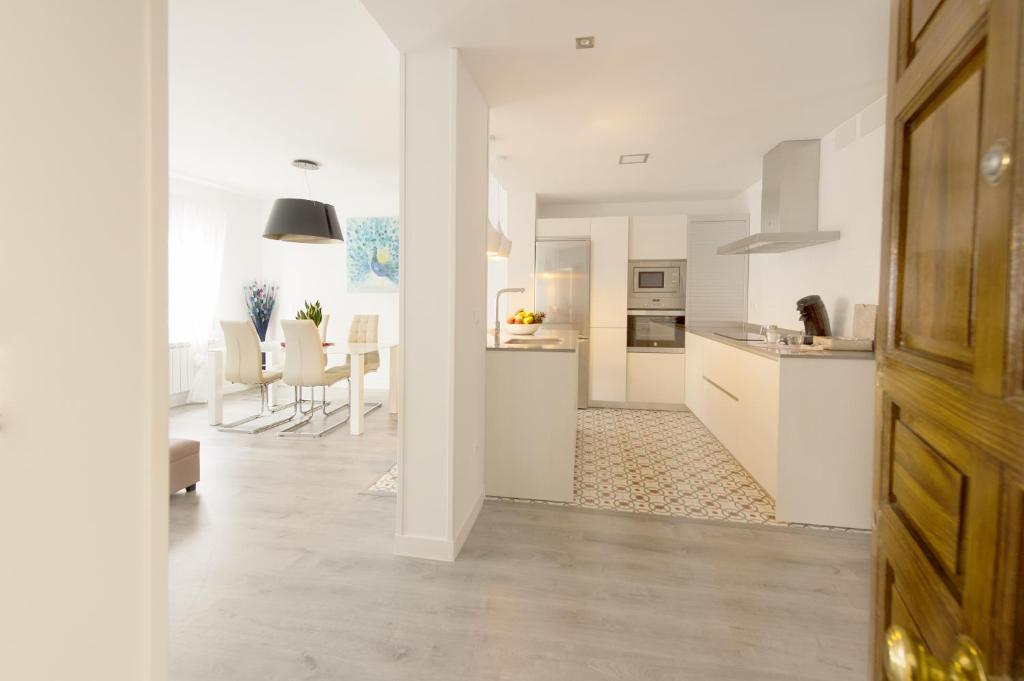 una cucina e un soggiorno con armadi bianchi e tavolo di Apartamento Turístico la Concordia a Guadalajara