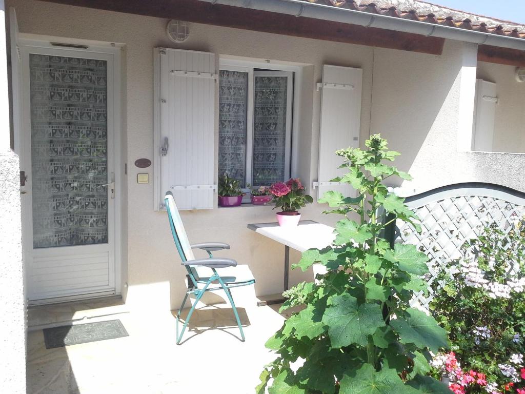 eine Veranda mit einem Stuhl, einem Tisch und einer Pflanze in der Unterkunft L'insulaire Studios in Saint-Denis-dʼOléron