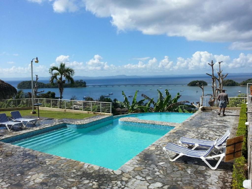 a swimming pool with chairs and a view of the water at Hidden Paradise at Apto Del Cerro in Santa Bárbara de Samaná