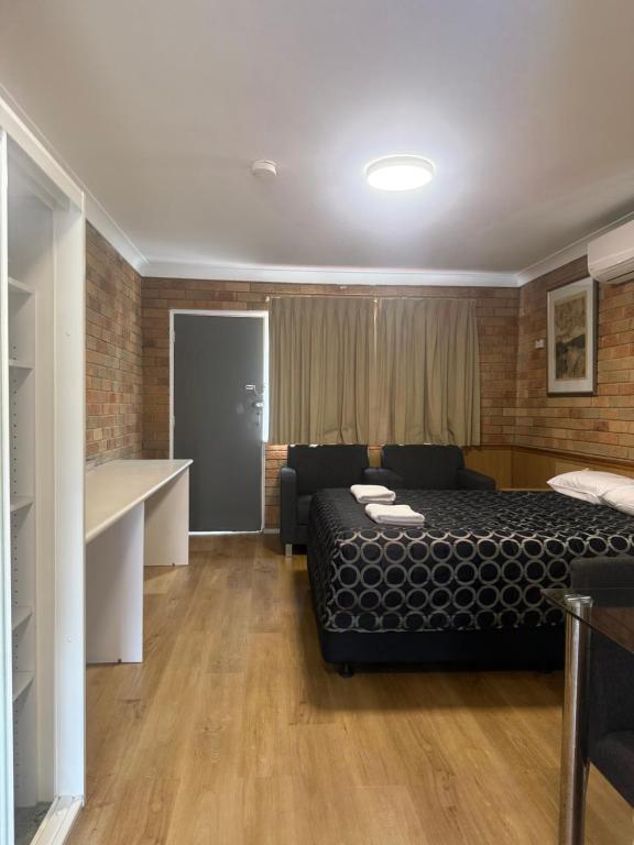 a bedroom with a bed and a couch in a room at Panorama Motor Inn in Newcastle