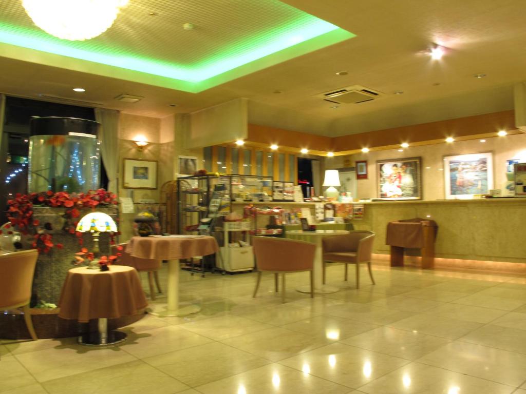 un restaurante con mesas y sillas y techo verde en Hotel Platon, en Chikuma
