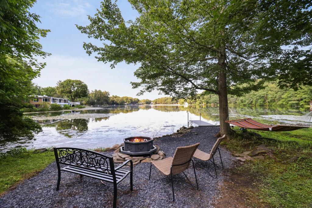 a fire pit with two chairs and a hammock next to a lake at Lakefront Haven Modern Cottage in Effort