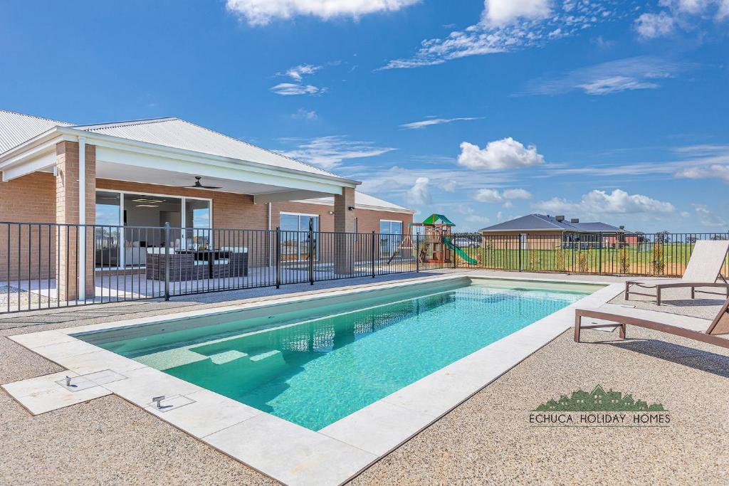 ein Swimmingpool vor einem Haus mit Spielplatz in der Unterkunft Riverside Meadows in Echuca