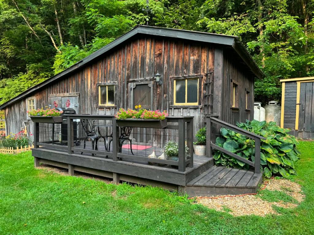 a small wooden cabin with a porch and flowers at The Renovated Barn at Seneca Rocks in Seneca Rocks
