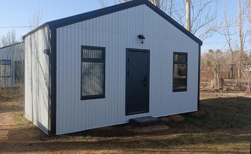 a small white shed with a black door at ИНХаус Т in Cholpon-Ata