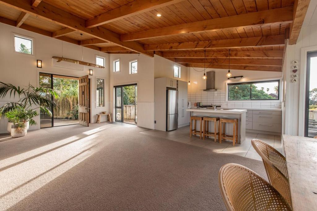 a large kitchen with wooden ceilings and a table and chairs at Tahana Villa - River View Retreat - 3 Bedroom in Oakura