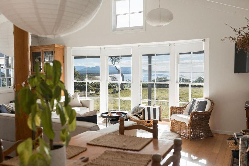 a living room with a view of the ocean at White Shell Cottage - Woodfire & Beachfront in Falmouth