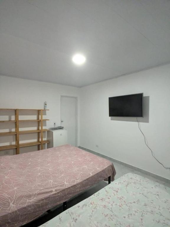 a bedroom with a bed and a tv on the wall at Residencial Scarparo in Iguape