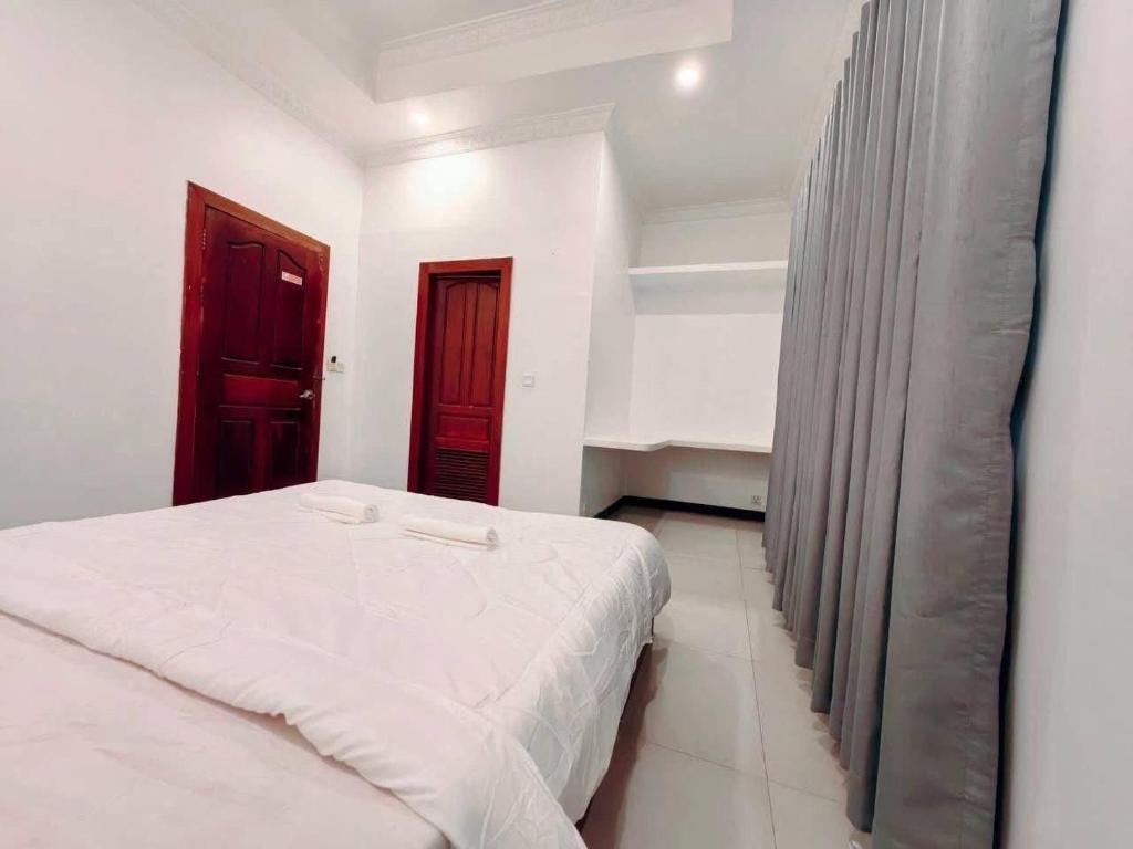 a bedroom with a white bed and a red door at Peace And Cool Hotel in Siem Reap