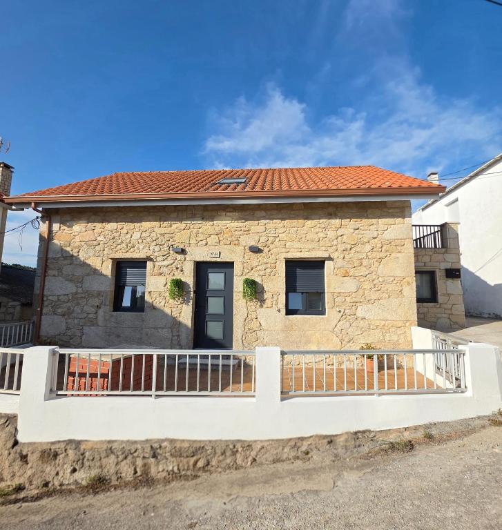 a stone house with a fence in front of it at Casa Zoila in Porto do Son