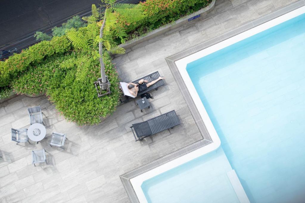 An overhead view of a bright rooftop pool beside a paved lounging deck.