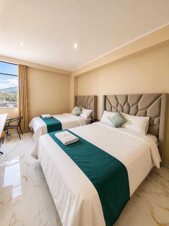 two beds in a hotel room with a window at Libertad Grand Hotel in Ayacucho