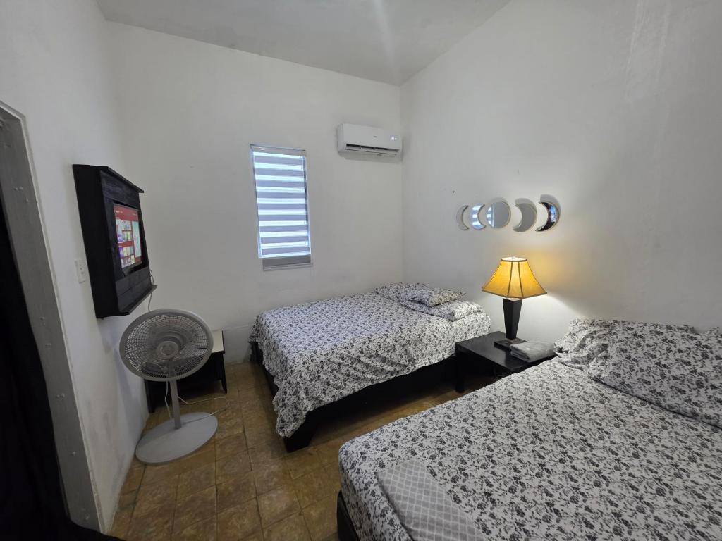 a bedroom with two beds and a fan and a window at Relax en el pueblo 1 in Fajardo