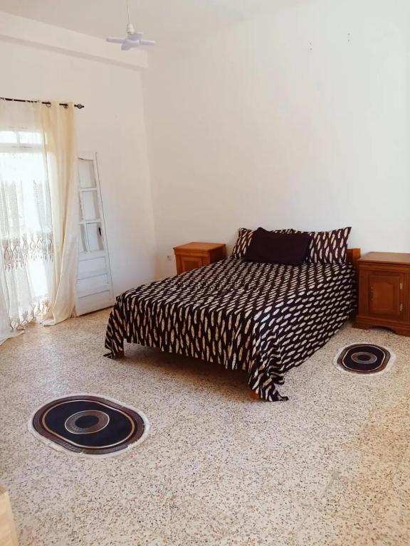 a bedroom with a bed with a black and white blanket at Appartement avec terrasse Vu sur mer in Rebaïb