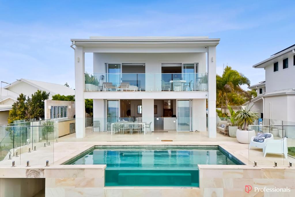 a house with a swimming pool in front of a house at Waters Edge On Wattle, Absolute Beachfront Luxury in Yeppoon