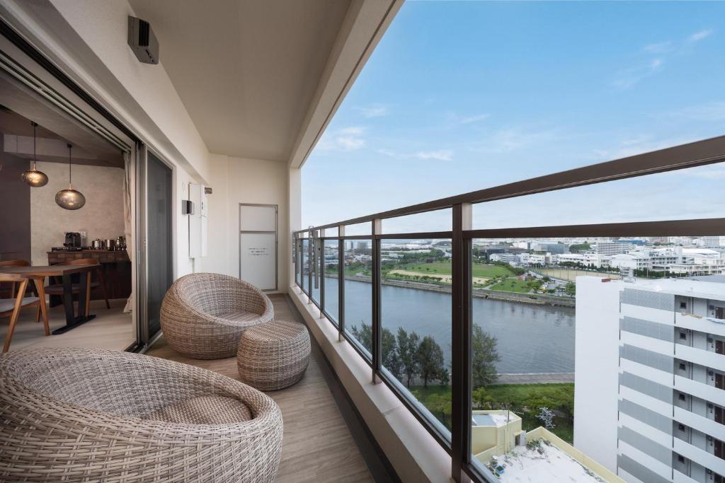 a balcony with wicker chairs and a view of the water at JAPAVISTA Casa De Boss in Naha
