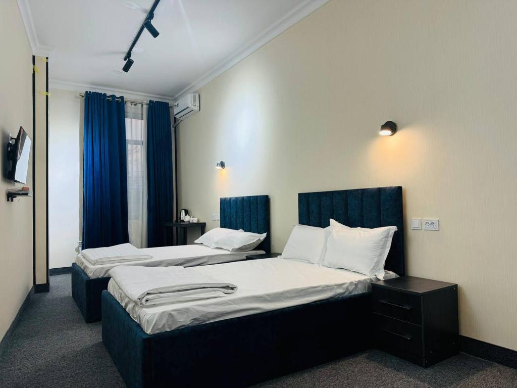 two beds in a hotel room with blue curtains at Backpackers Tashkent in Tashkent