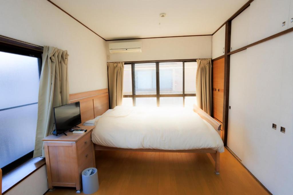 a bedroom with a bed and a tv and a window at Mikansei Stay in Higashi-murayama