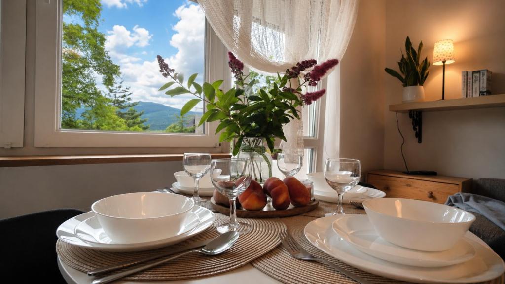 a table with plates and wine glasses and a window at Widokówka Karkonoska in Szklarska Poręba