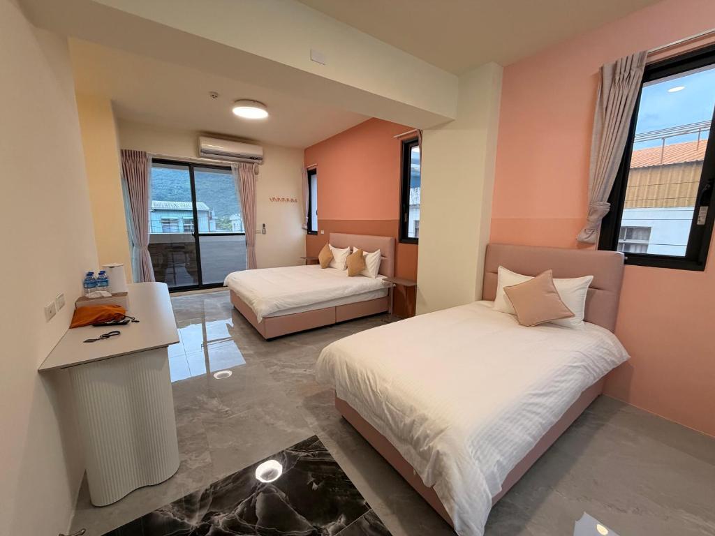 a bedroom with two beds and a desk and windows at 上好所在民宿 in Shoufeng