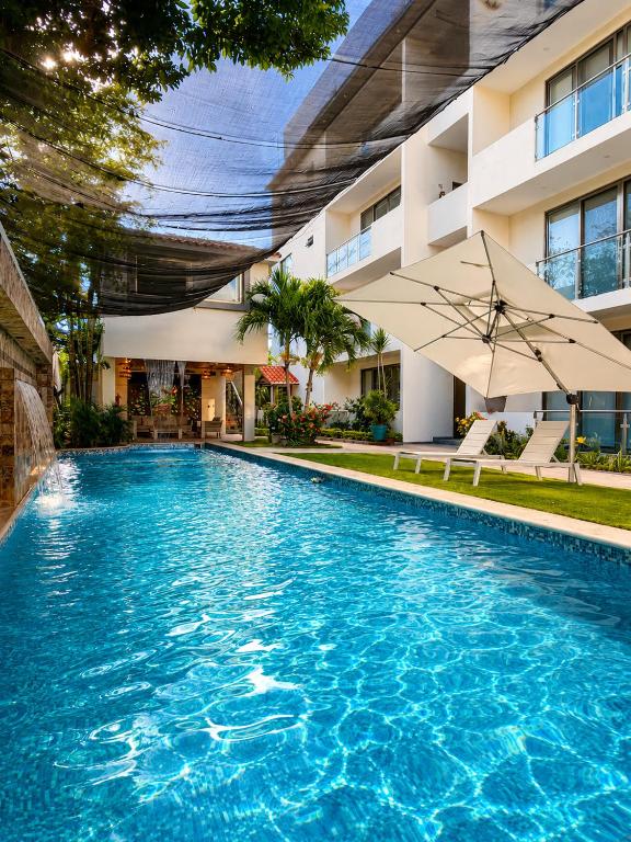 a swimming pool with an umbrella in front of a building at Akbal Cancun in Cancún