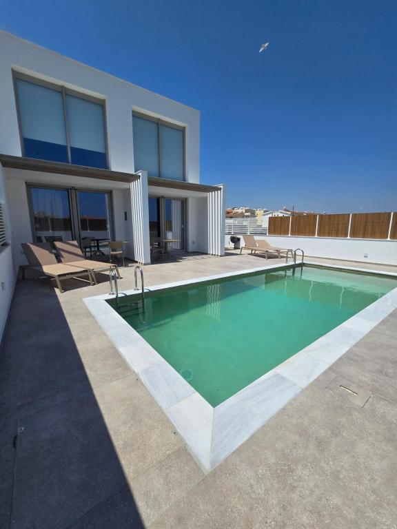 a swimming pool in front of a house at Divina Loft C Modern Loft with Shared Pool in Perivolia