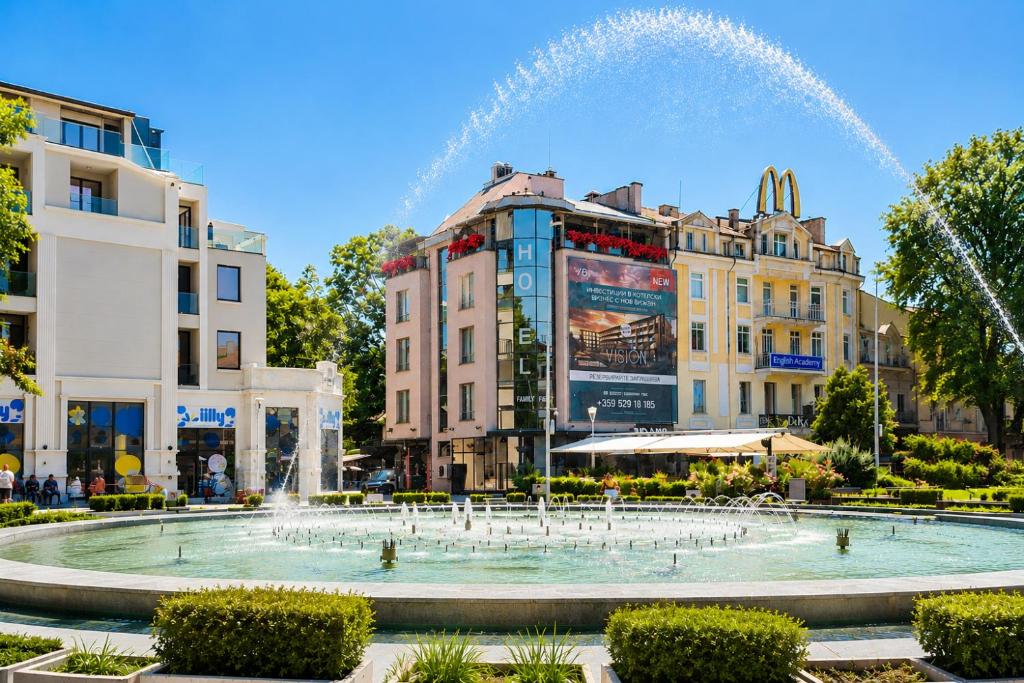 a fountain in the middle of a city with buildings at Opera Family Hotel - former City Mark hotel in Varna City