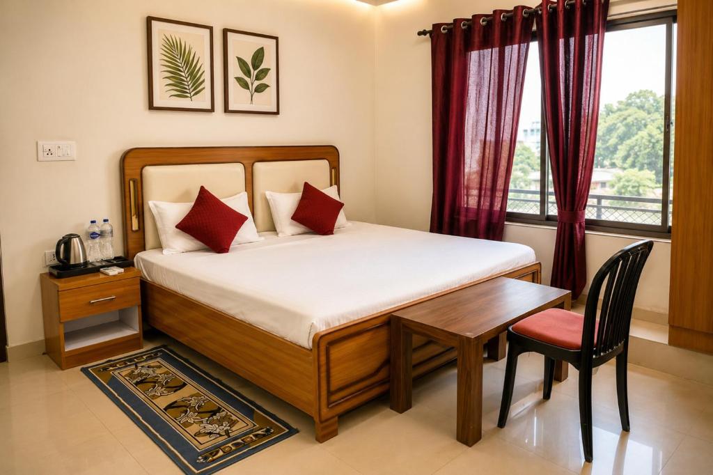 a bedroom with a bed and a table and a window at Hotel Jayaditya Palace in Ayodhya