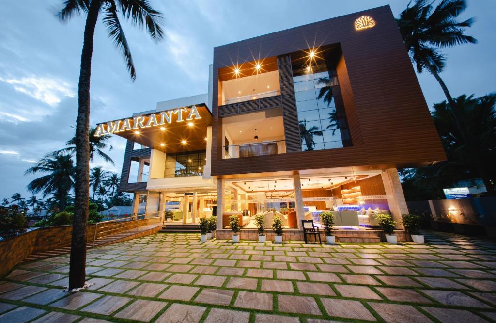 a building with a palm tree in front of it at Hanric by Eight Continents Amaranta, Varkala in Varkala