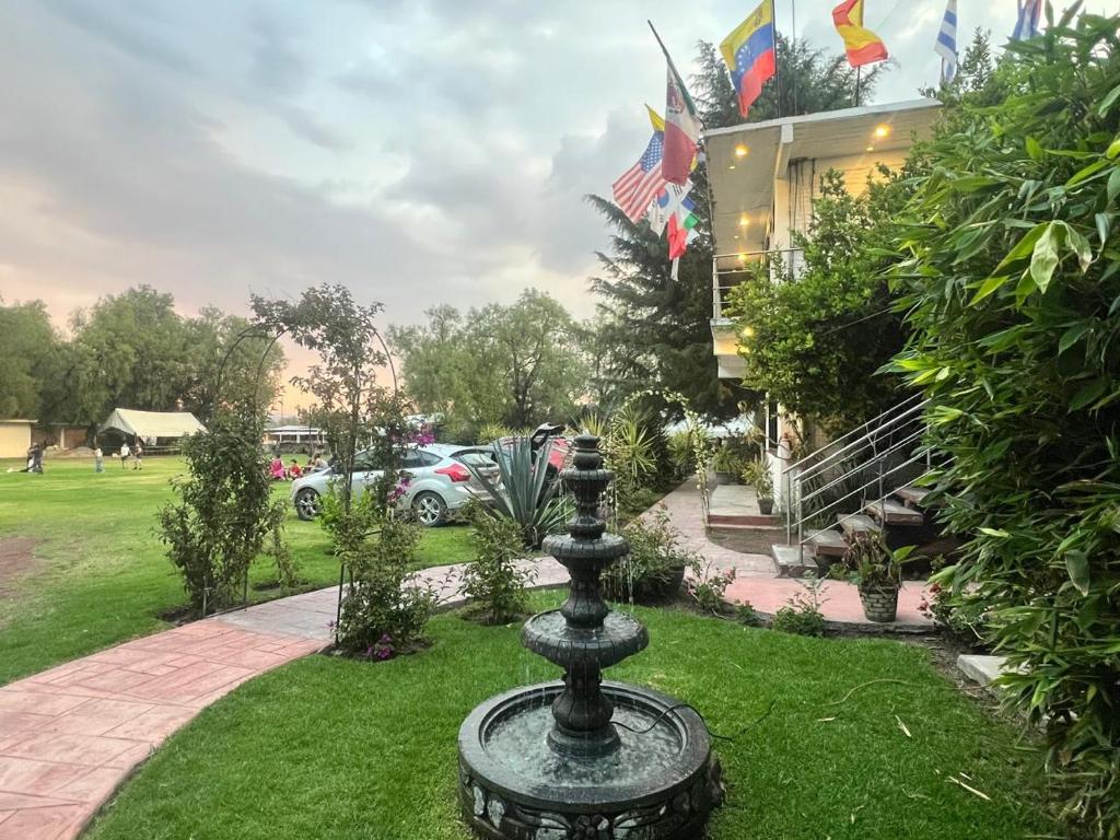 a fountain in the grass in front of a building at Telpochcalli Hotel & Temazcal in San Juan Teotihuacán