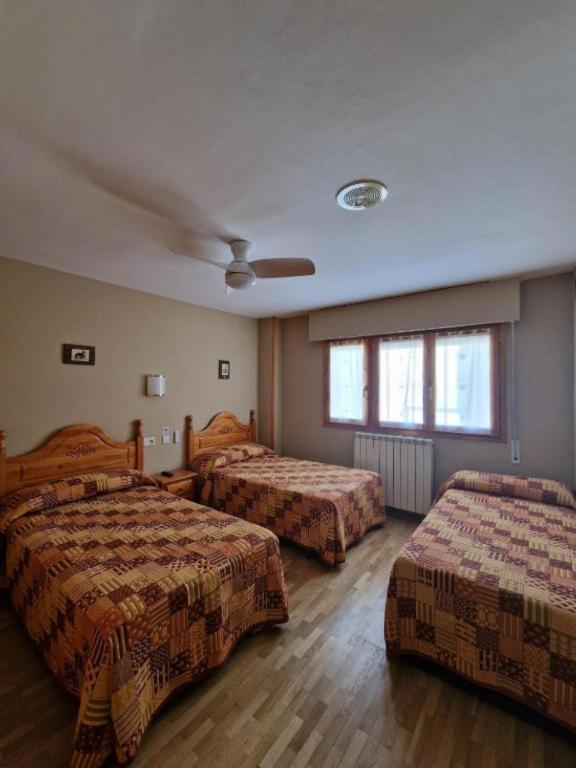a hotel room with two beds and two windows at Hostal Valle De Tena in Sabiñánigo