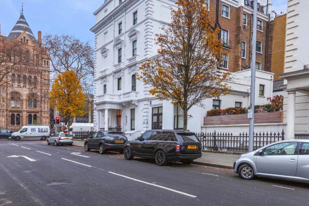 South Kensington Apartment x4 في لندن: مجموعة من السيارات تقف على جانب شارع المدينة