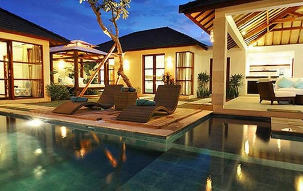 a house with a swimming pool in front of a house at Arama Riverside in Legian