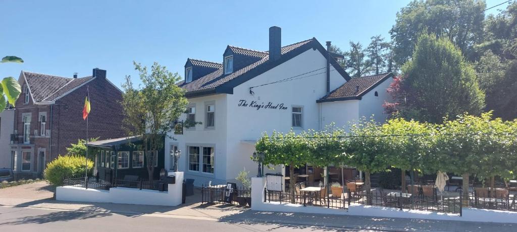 a white building with tables and chairs in front of it at Hotel Restaurant The Kings Head Inn in Voeren
