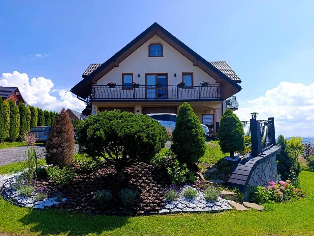 a house with a balcony on top of a yard at Pokoje Widok Szlembark in Szlembark