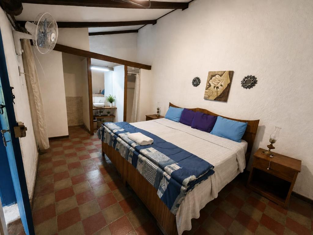 a bedroom with a large bed with blue pillows at Hostal Casona de los Vega in Sonsonate