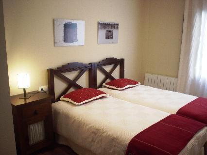 1 dormitorio con 1 cama con 2 almohadas rojas en Casa Rural Descanso del Quijote, en Belmonte