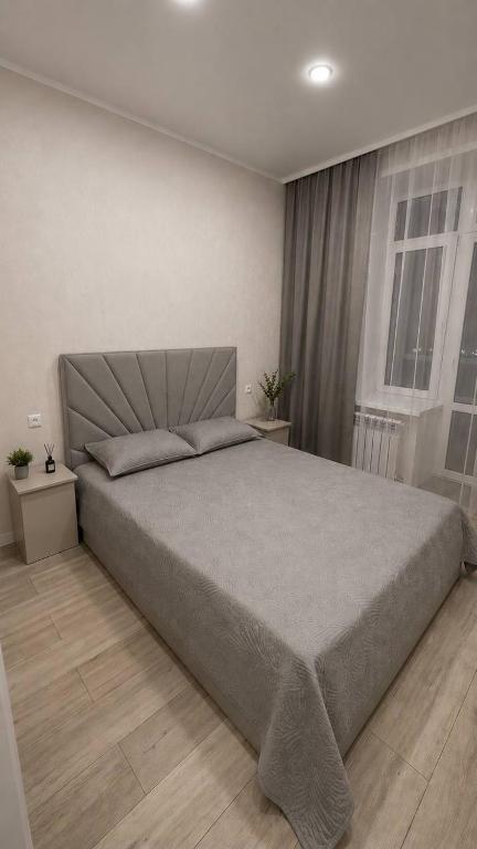 a bedroom with a large bed and two windows at Алпамыс - В пешей доступности Центральный парк, ЦУМ, ТРЦ MART in Kostanay