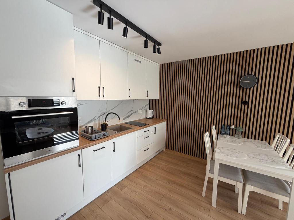 a kitchen with white cabinets and a table with chairs at Piast Castle Apartment Brzeg in Brzeg