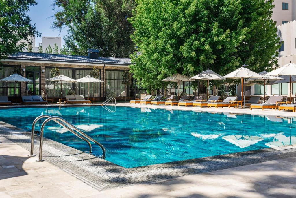a large swimming pool with chairs and umbrellas at Radisson Blu Hotel, Tashkent in Tashkent